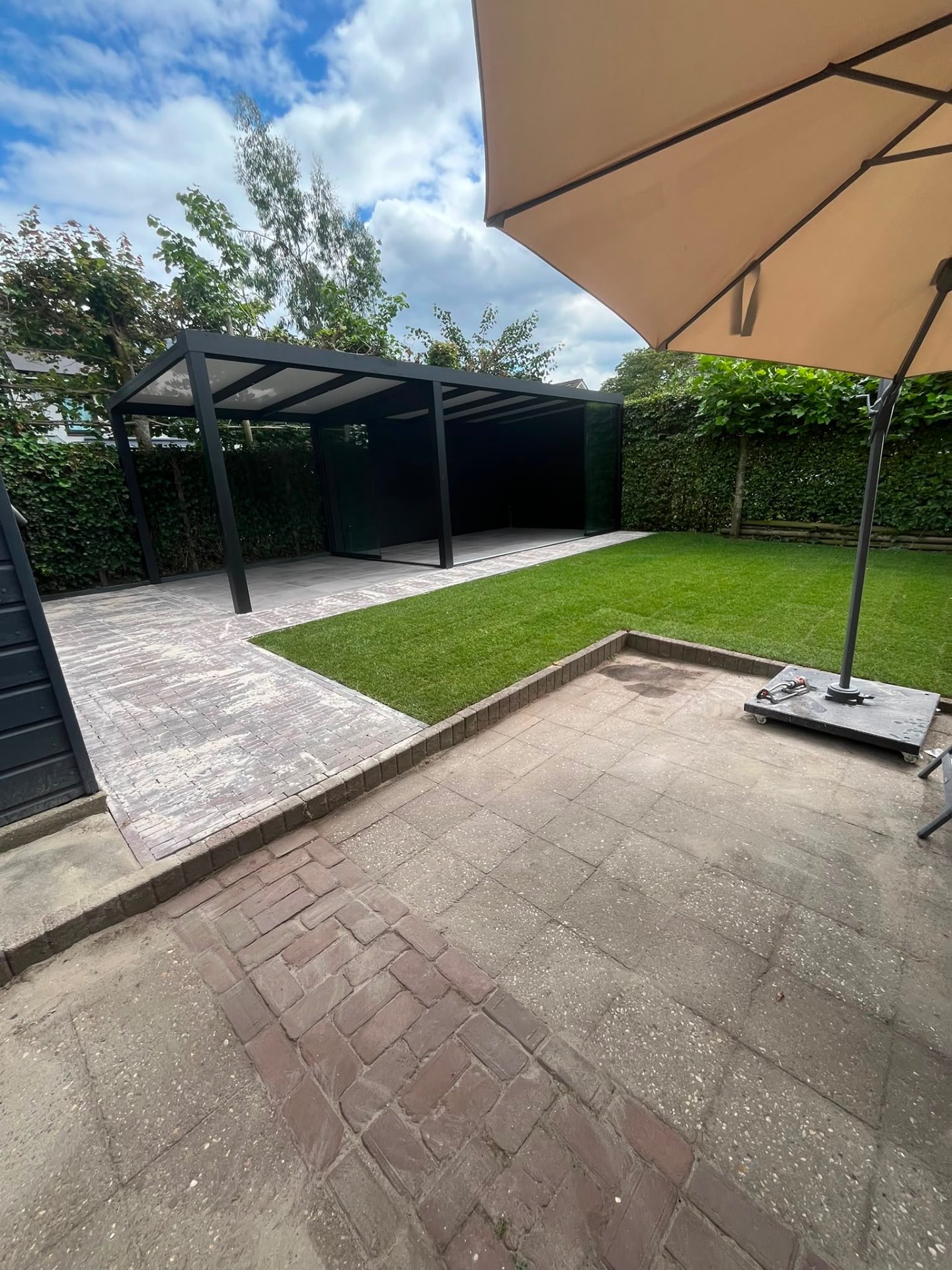 Achtertuin met overkapping, kunstgras & sierbestrating